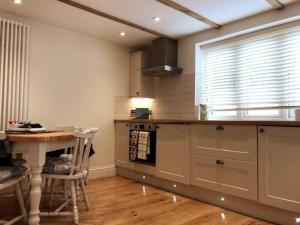 a kitchen with a counter and a table and a window at Folly Cottage & The Old Forge in Colerne