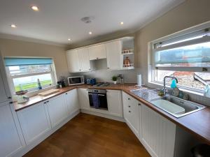 a kitchen with white cabinets and a sink at Extended Fishermans cottage with stunning sea views in The Mumbles