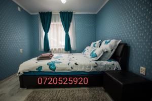 a bedroom with a bed with blue walls and a window at Cazare La Piatra Buhei in Câmpulung Moldovenesc