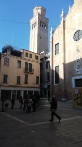 een groep mensen die door een stad lopen met een klokkentoren bij Ca al Campanile in Venetië