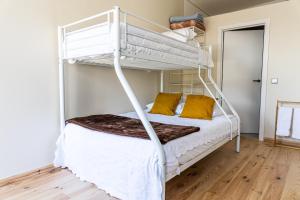 a bedroom with a white bunk bed with yellow pillows at House on a rustic Island At Campanha Trainstation in Porto