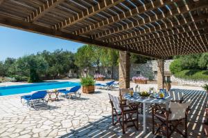 a patio with a table and chairs and a swimming pool at Villa Barba Yannis in Gaios