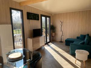 a living room with a blue couch and a tv at Au fil de l’eau, gîte nature in Abbécourt