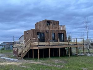 a large wooden house on a wooden deck at Au fil de l’eau, gîte nature in Abbécourt