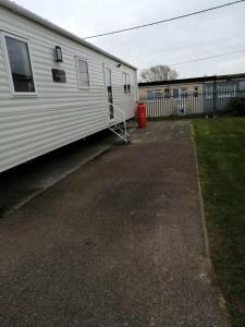 um reboque branco estacionado ao lado de um edifício em 709 Seawick em Jaywick Sands