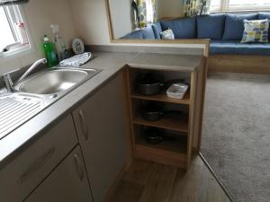uma pequena cozinha com um lavatório e um sofá em 709 Seawick em Jaywick Sands