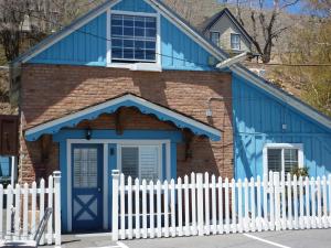 una casa azul con una valla blanca delante de ella en Sugarloaf Mountain Motel en Virginia City
