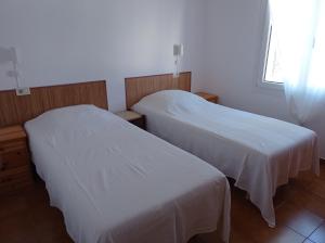 two beds in a room with white sheets at Can Eugeni in L'Escala +15 photos