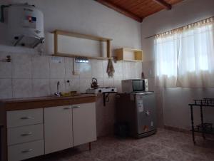 a small kitchen with a refrigerator and a microwave at Cabañas de Descanso Céntricas Cosquín in Cosquín