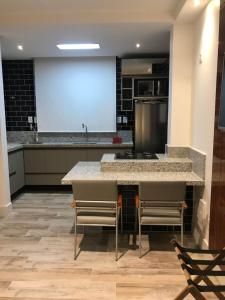a large kitchen with a large counter top and chairs at Flats Monsenhor31 - Localizado no centro da cidade in Paulo Afonso