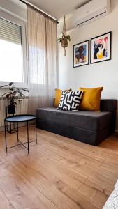 a living room with a black couch and a table at Studio apartman Siget II in Zagreb