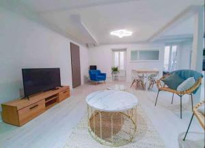 a living room with a flat screen tv and a table at Le Nuits Saint Georges in Nuits-Saint-Georges