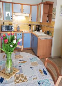a kitchen with a table with a vase of flowers on it at Appart Bord de Mer, 6 PLaces, Plage à 250 m, Dune, Parking gratuit, Rez de Chaussée surélevé in Saint-Hilaire-de-Riez