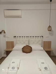 un letto bianco con un cappello sopra di Bamboo Luxury Studios a Nikiti