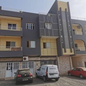 dos autos estacionados en un estacionamiento frente a un edificio en Ellen Apartamentos en Espargos