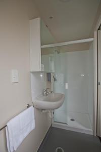 uma casa de banho branca com um lavatório e um chuveiro em City Lodge Accommodation em Auckland
