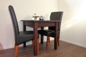 a wooden table with two black chairs and a table with flowers at Logement de Garage in Sneek