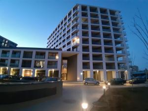 Un gran edificio con coches aparcados en un estacionamiento. en Apartament Pianista, en Varsovia