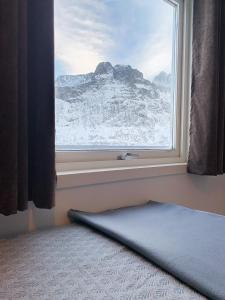 une fenêtre avec vue sur une montagne enneigée dans l'établissement Segla Guesthouse - Lovely sea view, à Fjordgård