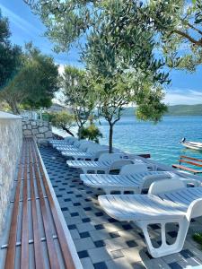 - une rangée de chaises longues blanches à côté de l'eau dans l'établissement Villa Millene, à Neum