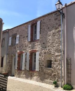 un antico edificio in pietra con finestre e un lampione di Le logis de la Forge à 10 min du Puy duFou a Mortagne-sur-Sèvre