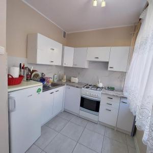 Il comprend une petite cuisine avec des placards blancs et une cuisinière. dans l'établissement Apartament L14, Mieszkanie dla Wszystkich, à Konin
