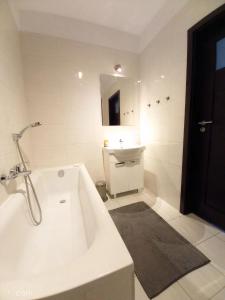 ein weißes Badezimmer mit einer Badewanne und einem Waschbecken in der Unterkunft Apartamenty Warszawskie delux Siedmiogrodzka in Warschau