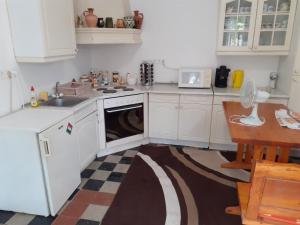a kitchen with white cabinets and a sink and a dishwasher at Bella Apartman in Sárospatak