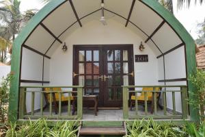 a small house with a arched doorway and yellow chairs at Pause By The Sea in Morjim