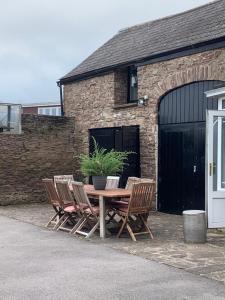 a wooden table with four chairs and a potted plant at Highfield Barn Loft in Portishead