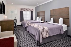 ハンブルにあるAmericas Inn & Suites IAH Northのベッド2台とデスクが備わるホテルルームです。