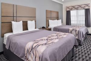 a hotel room with two beds and a window at Americas Inn & Suites IAH North in Humble