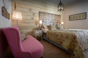 ein Schlafzimmer mit einem Bett und einem rosa Stuhl in der Unterkunft Karstorp Säteri – Hotell och Konferens in Skövde