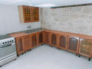 a kitchen with wooden cabinets and a sink and a stove at Casa das Mareas in Muros
