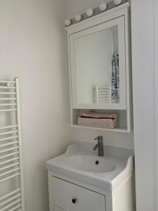 La salle de bains blanche est pourvue d'un lavabo et d'un miroir. dans l'établissement Beau T2 clim terrasse idéalement situé, à Aix-en-Provence