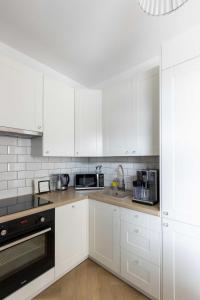 uma cozinha branca com armários brancos e um micro-ondas em Apartament Zagnańska Patio Vita- z garażem podziemnym em Kielce