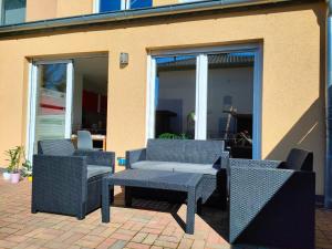 three wicker chairs and a table on a patio at Tolle Wohnung in Fontanestadt Neuruppin in Neuruppin