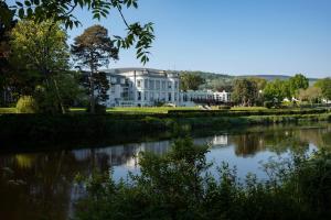 a large white house sitting next to a river at Hotel Minella & Leisure Centre in Clonmel
