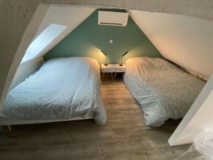 2 camas en un dormitorio del ático con una pared verde en Logement Loire climatisé, La Halte de Cuze, aux abords de la Loire a vélo, en Huismes