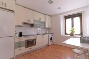 a kitchen with white cabinets and a sink and a table at Herradores Centro in Soria