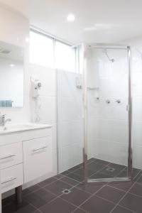 baño blanco con ducha y lavamanos en Narellan Motor Inn en Narellan