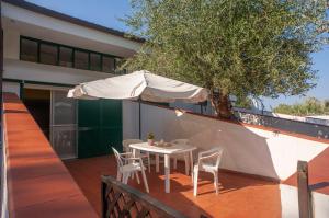 eine Terrasse mit einem Tisch, Stühlen und einem Sonnenschirm in der Unterkunft Casa Palinuro Vacanze in Palinuro