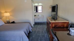 Cette chambre comprend un lit et une télévision à écran plat. dans l'établissement Queen City Inn, à Bangor