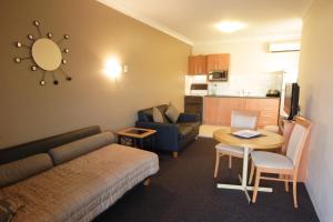 Habitación con sofá, mesa y cocina. en Narellan Motor Inn en Narellan