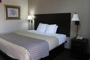 a hotel room with a large bed and a phone at Savannah Inn - Savannah I-95 North in Port Wentworth