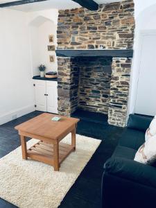 a living room with a table and a stone fireplace at Little Bere apartment in Lifton