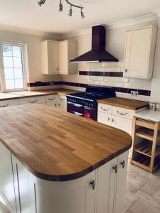 a kitchen with white cabinets and a wooden counter top at Little Bere apartment in Lifton