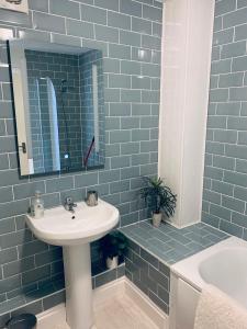 a bathroom with a sink and a mirror and a tub at Little Bere apartment in Lifton