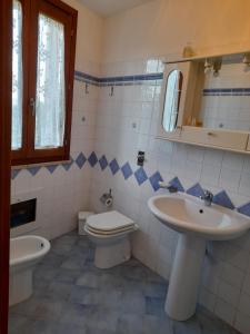 een badkamer met een wastafel, een toilet en een spiegel bij Casa di Jacu in Favignana