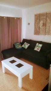 a living room with a black couch and a white coffee table at Tropical Canary Home - Playa Del Ingels in Playa del Ingles